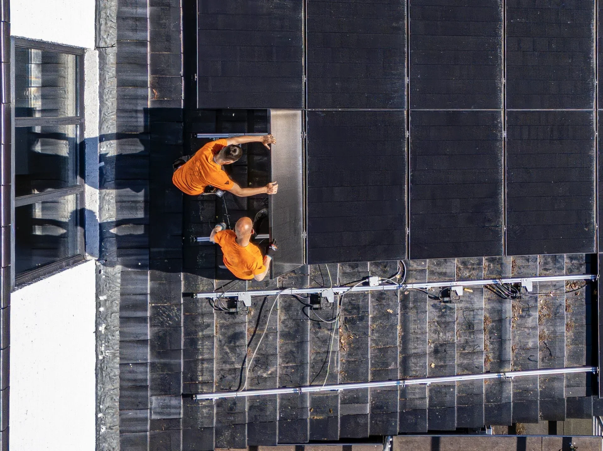 Hoeveel zonnepanelen nodig? Installateurs op het dak laten zien hoe ze een zonnepanelen neerleggen