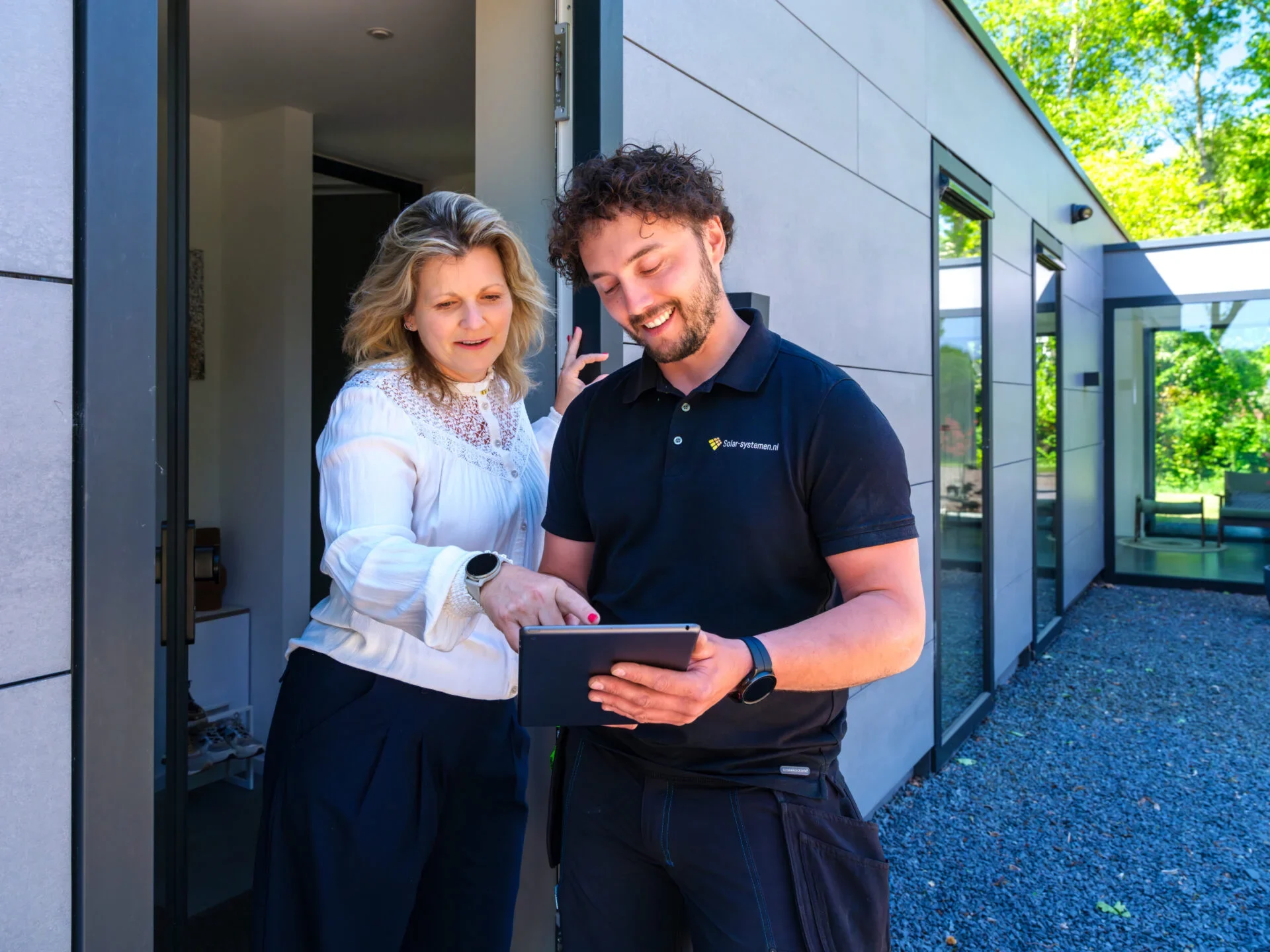 Hoeveel leveren zonnepanelen op? Installateur laat het zien aan een mevrouw op de tablet